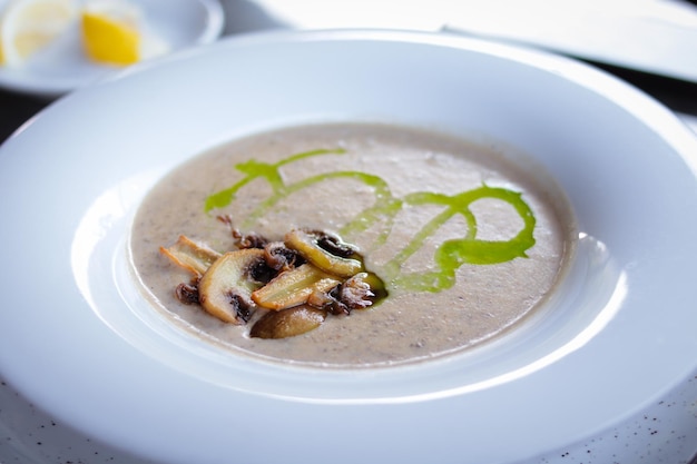 Foto der Suppe mit Pilzen. Suppe in einer schönen weißen Schüssel mit Champignons.