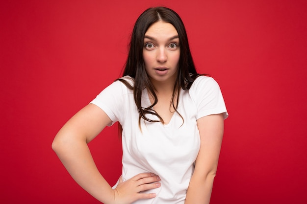 Foto der überraschten jungen schönen Brunet-Dame mit aufrichtigen Gefühlen, die lässiges weißes T-Shirt für trägt