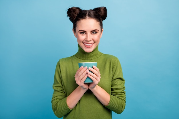 Foto der ziemlich attraktiven charmanten Dame Teenager halten heißes Getränk Tasse Tee Kaffee genießen Morgen tragen warme grüne Rollkragenpullover isoliert blau Farbe Wand