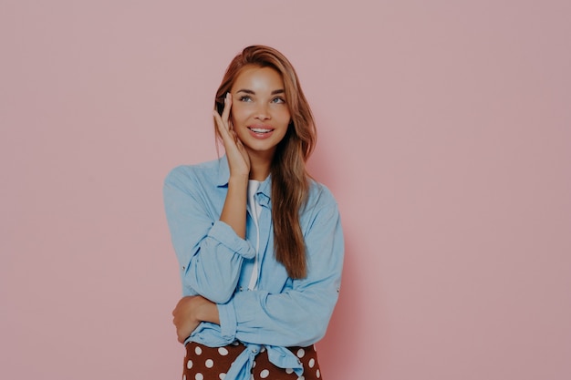 Foto des angenehm aussehenden weiblichen Models berührt die Wange mit der Hand