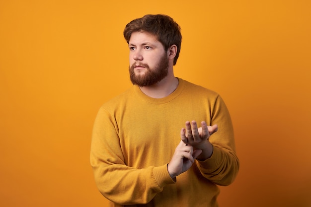 Foto des attraktiven Mannes trägt runde Brille, hält Hand am Handgelenk, prüft Puls oder Herzfrequenz, kümmert sich um seine Gesundheit, hat Herzklopfen, Modelle vor weißem Hintergrund