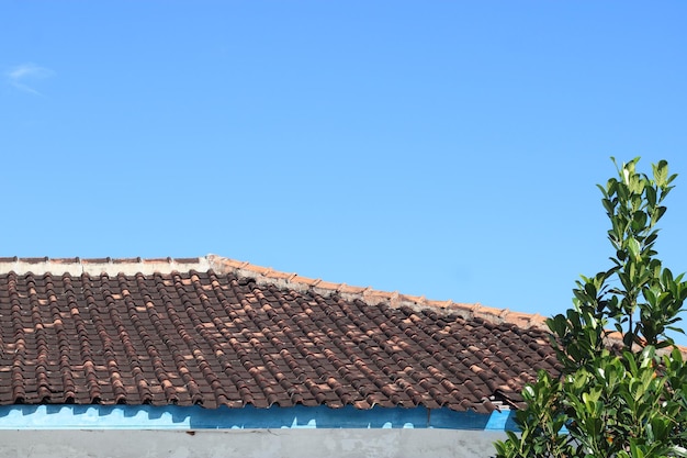 Foto des blauen Himmels über den Dachziegeln des Hauses