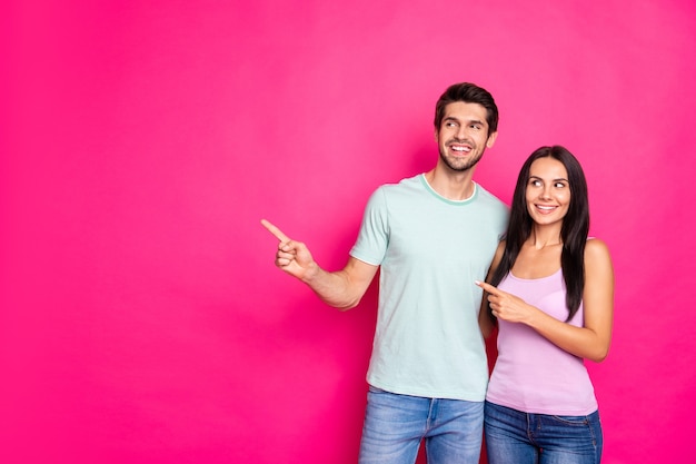 Foto des erstaunlichen Paares Kerl und Dame, die Finger zum leeren Raum anzeigt, der schwarzen Freitageinkauf empfiehlt, tragen lässige Kleidung lokal lebendigen rosa Farbhintergrund
