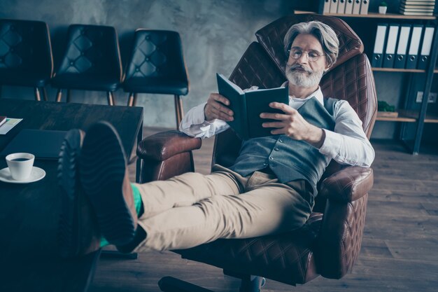 Foto foto des fokussierten geschäftsmanns sitzen stuhl lesen organisator im büro