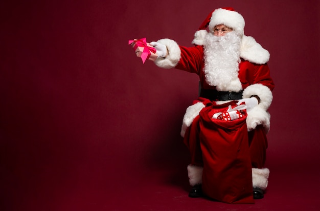 Foto des glücklich lächelnden Weihnachtsmanns mit Geschenkboxen wirft auf