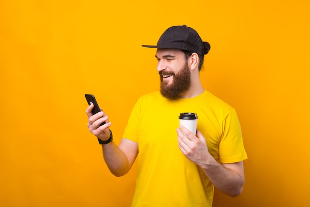 Foto des glücklichen Mannes, der eine Pause vom Job hat, der Kaffee trinkt und Telefon benutzt