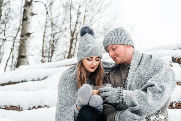 Foto des glücklichen mannes und der hübschen frau mit tassen im freien im winterurlaub und im urlaub. weihnachtspaar verliebt.