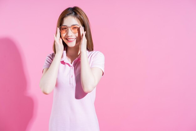 Foto des jungen asiatischen Mädchens, das auf rosa Hintergrund aufwirft