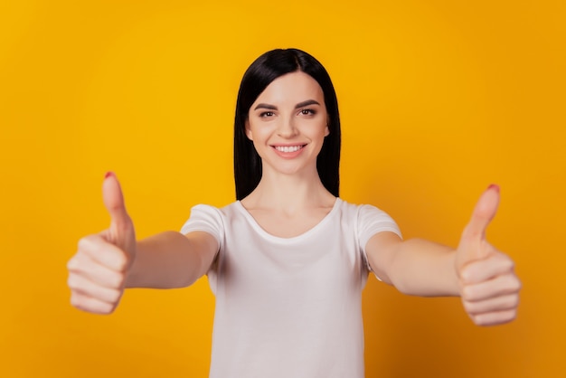 Foto des jungen attraktiven Mädchens glückliches positives Lächeln zeigen Daumen hoch perfekt wie Werbung einzeln auf gelbem Farbhintergrund