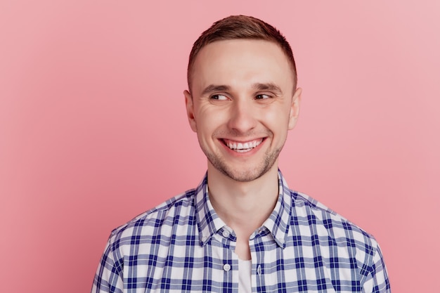 Foto des jungen fröhlichen Kerls glückliches positives Lächeln beiläufiges Outfit sieht leer aus, isoliert über rosafarbenem Hintergrund