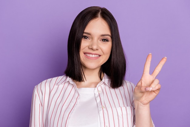 Foto des jungen fröhlichen Mädchens zeigt Finger Frieden cool vsymbol Urlaub isoliert über violettem Farbhintergrund