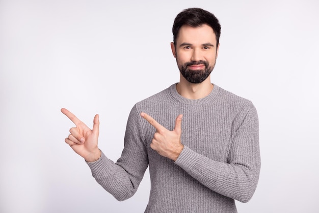 Foto des jungen Kerls gute Laune zeigt Finger leeren Raum Promoter beraten Anzeigen isoliert über grauem Hintergrund