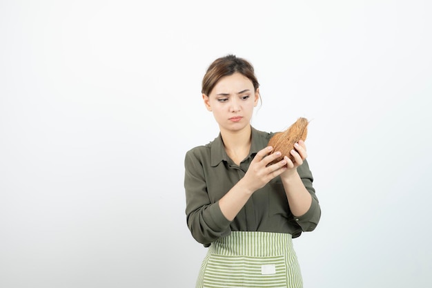 Foto foto des jungen mädchens, das haarige kokosnuss über weiß betrachtet. foto in hoher qualität