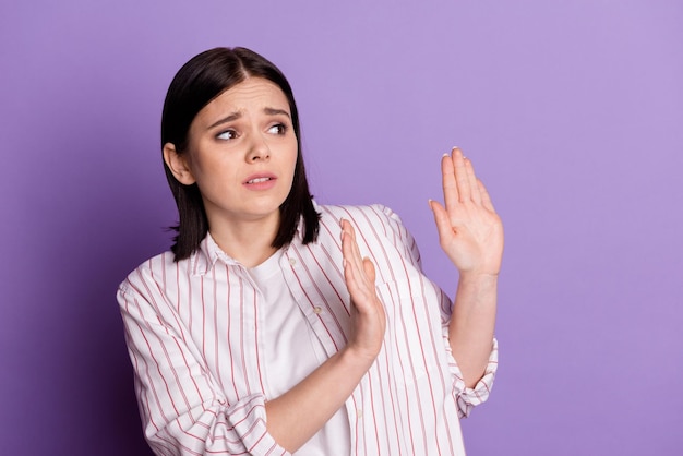 Foto des jungen Mädchens verängstigt, besorgt, ängstlich, leerer Raum, zeigt Hände, die Zeichen ablehnen, isoliert über violettem Farbhintergrund