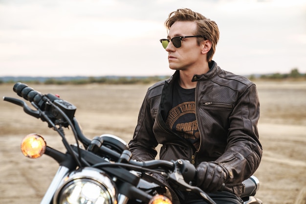 Foto des jungen Mannes Biker auf dem Fahrrad draußen auf dem Wüstenfeld.