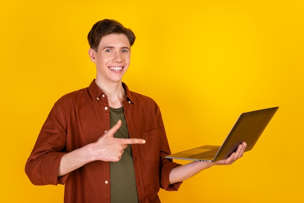 Foto des jungen Mannes zeigt Finger-Laptop-Werbeaktion ausgewählten Rabatt an, der über gelbem Farbhintergrund isoliert ist