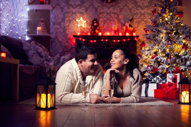 Foto des jungen Paares, das durch den fireplaec im Weihnachtsraum stillsteht. Weihnachten feiern. Weihnachtsbaum.