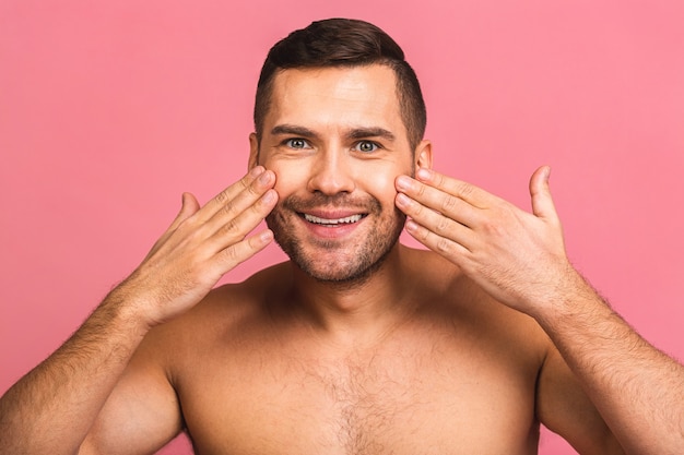 Foto des lächelnden jungen schönen Mannes, der nackt steht. Mann-Hautpflegekonzept in einem Badezimmer.