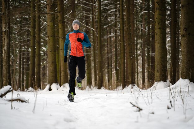 Foto des laufenden Athleten unter Bäumen im Winterwald