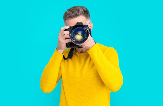 Foto des Mannfotografen mit Kameraobjektiv Mannfotograf mit der Kamera lokalisiert auf Blau