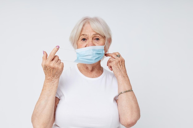 Foto des medizinischen Maskenschutzes der alten Dame im Ruhestand, heller Hintergrund