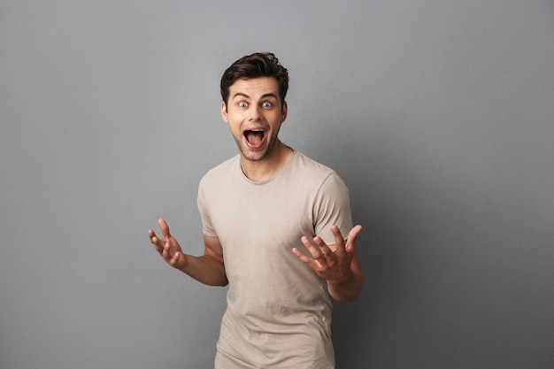 Foto des positiven jungen Kerls, der mit Freude gestikuliert und schreit