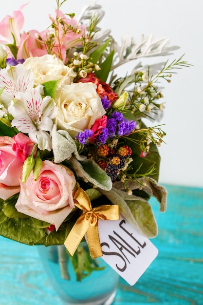 Foto des romantischen Blumenstraußes von rosa Rosen, Lilien, grünen Blättern mit Postkarte auf hölzerner blauer Oberfläche