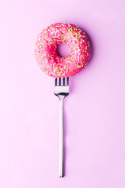 Foto des rosa Donuts auf Gabel am leeren Hintergrund