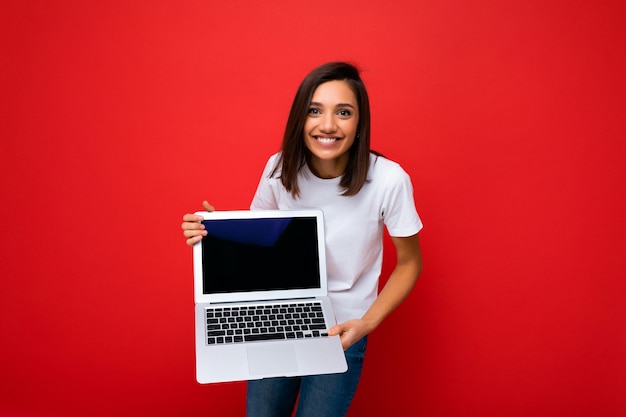 Foto des schönen jungen Mädchens, das Computer-Laptop hält Kamera betrachtet