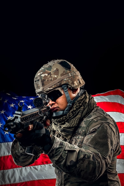 Foto des Soldaten, der die USA-Flagge im Hintergrund hält. Special Force US-Soldat oder Militärunternehmer, die Gewehr halten. Bild im Hintergrund. Soldat, Armee, Krieg, Waffen und Technologiekonzept.