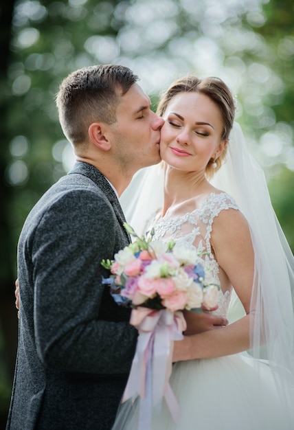 Foto desfocada do casal de noivos segurando colorido buquê de rosas