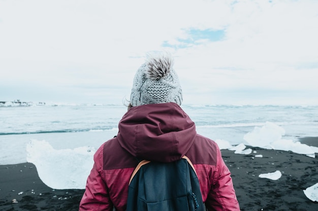 Foto de detrás de una mujer frente a un glaciar en islandia viajes de invierno concepto de clima frío