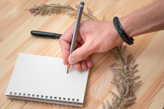 Foto de dibujo en la libreta de mano masculina con pulsera