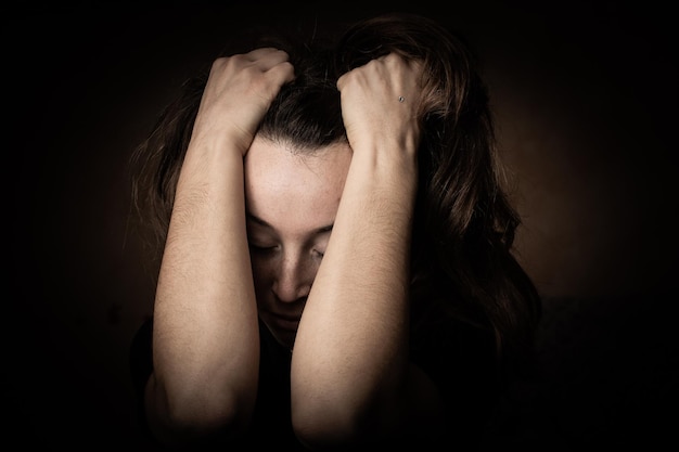 Foto discreta de jovem deprimida chorando vítima de violência doméstica menina assustada sentada com a cabeça nas mãos emoções no rosto feminino violência contra as mulheresxdxa
