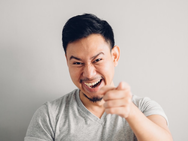 Foto de disparo en la cabeza del hombre asiático con cara de risa sobre fondo gris.