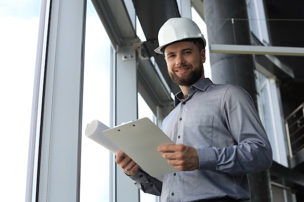 Foto do arquiteto masculino usando capacete de segurança e inspecionando o novo edifício.