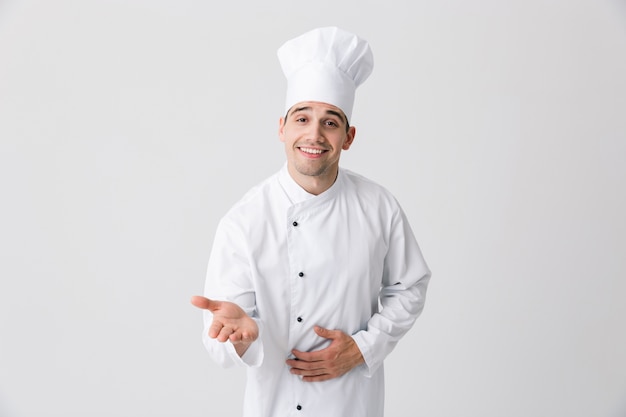 Foto do chef de jovem bonito dentro de casa isolada sobre posar de fundo de parede branca.