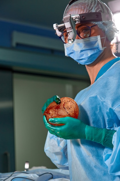 Foto do cirurgião operacional na sala de cirurgia. Cirurgião em máscara e óculos com farol montado. Fechar retrato