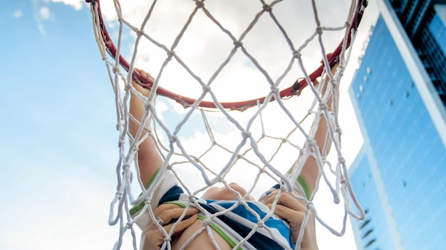 Foto do close up do menino ativo da criança de 3 anos segurando o anel da rede de basquete. conceito de crianças ativas e desportivas. saúde das crianças da nova geração