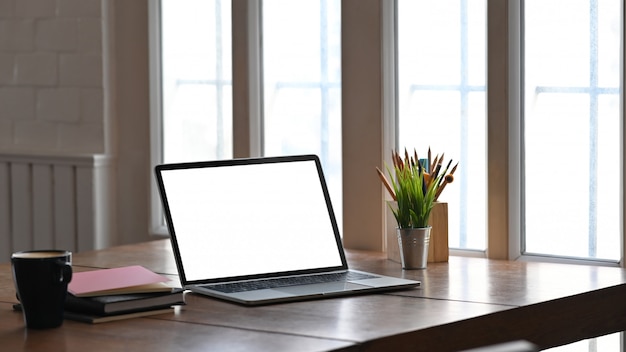 Foto do computador de tela em branco branco colocando na mesa de madeira, juntamente com vasos de plantas