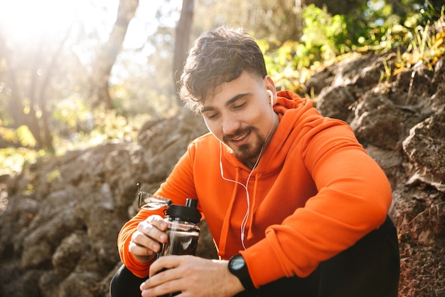 Foto do corredor de homem de aptidão de esportes jovem bonito ao ar livre no parque de água potável.