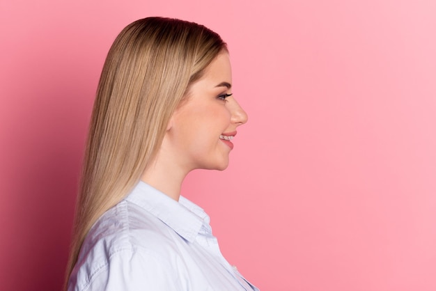 Foto do lado do perfil de uma jovem alegre parece especialista em espaço vazio inteligente isolada sobre fundo de cor rosa