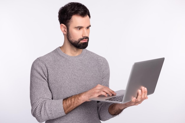 Foto do lado do perfil do jovem empresário, veja o projeto de e-mail de bate-papo, navegue no laptop isolado sobre o fundo de cor cinza