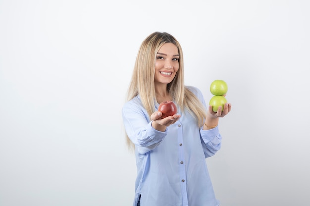 Foto do retrato de um modelo de mulher muito atraente em pé e segurando maçãs frescas.