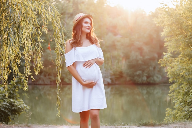 foto do sol. roupas para mulheres grávidas. menina grávida sorrindo sonhadora