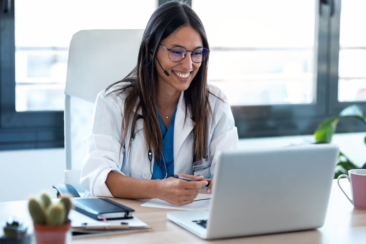 Foto foto de doctora hablando con colegas a través de una videollamada con una computadora portátil en la consulta.