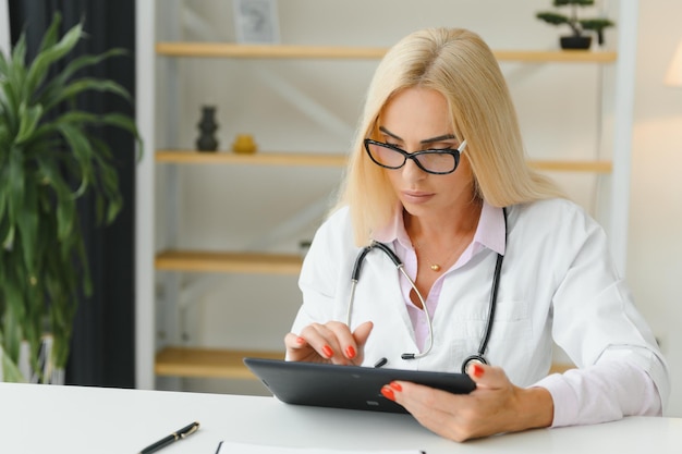 Una foto de una doctora trabajando sentada en el escritorio frente a una laptop