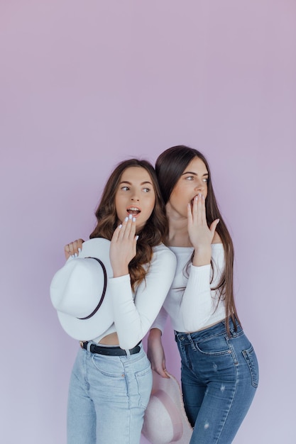 Foto foto de dos amigas emocionales que se encuentran aisladas sobre un fondo morado.