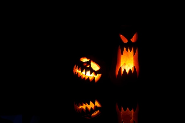 Foto foto de dos calabazas de halloween con bocas ardientes sobre fondo negro vacío