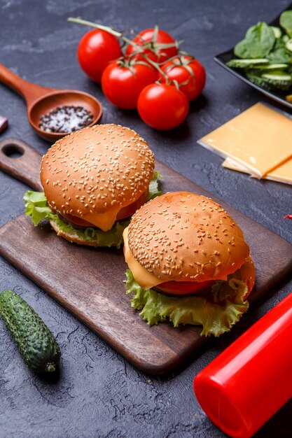 Foto de dos hamburguesas sobre tabla de madera, queso